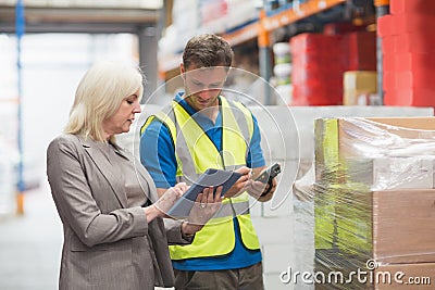 Manager using tablet while worker scanning package Stock Photo