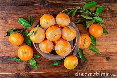 Mandarins tangerines in a ceramic bowl on wooden table. Top view Stock Photo