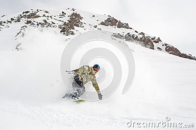 Manful snowboarder riding down the slope in the mountain resort Stock Photo