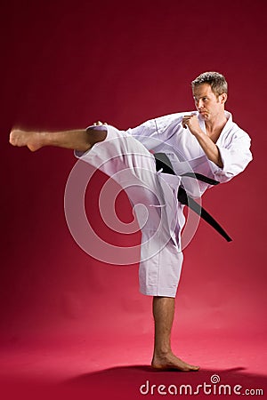 Mani in karate kimono kicking Stock Photo