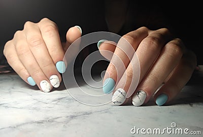 Manicure with glossy blue solid coating and marble design. Stock Photo