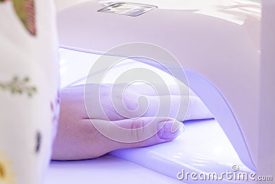 Manicure. hand in UV lamp. drying gel varnish in the lamp Stock Photo