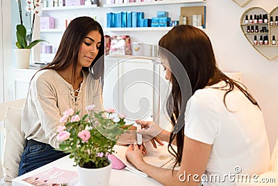 Manicure nail care for the client sitting at a table in the office. Stock Photo