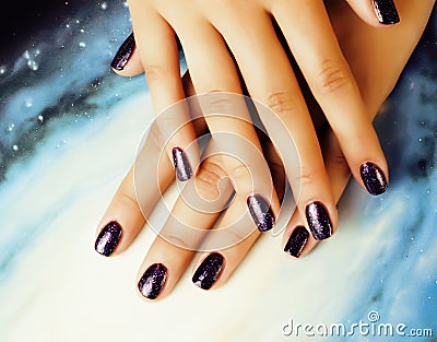 Manicure stylish concept: woman fingers with nails purple glitter on nails like cosmos, universe background Stock Photo