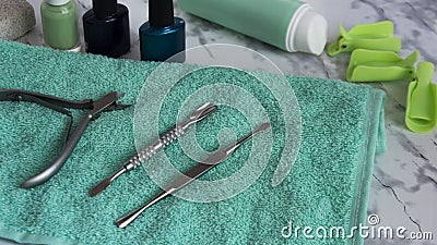 Manicure tools in the beauty salon or in the nail salon on a green towel with varnish and clips on a marble table. Tongs, knife Stock Photo