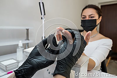The manicurist covers the client`s nails with red varnish. Manicure in a beauty salon Stock Photo