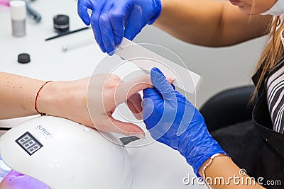 Manicurist makes the procedure a woman in nail salon Editorial Stock Photo