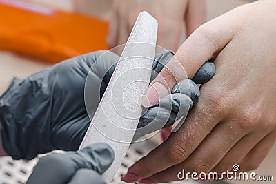 The manicurist makes sawdust and shaping of the nail after correction or length extension Stock Photo