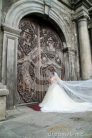 Bride in wedding dress and veil waiting outside old church Editorial Stock Photo