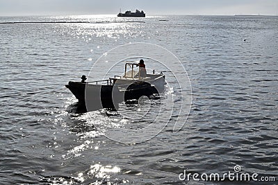Man driving small tugboat toward the sea shore Editorial Stock Photo