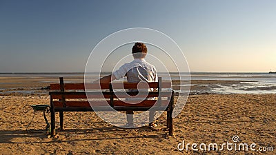 Mann, der allein auf dem Strand sitzt stock video footage Mann, der allein auf dem Strand sitzt stock video footage