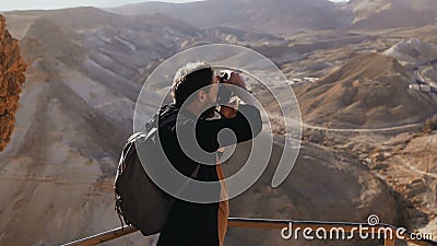 Mann macht Fotos der erstaunlichen Wüstenlandschaft Europäischer männlicher Tourist mit Kamera am enormen Bergblick Israel 4K stock video footage Mann macht Fotos der erstaunlichen Wüstenlandschaft Europäischer männlicher Tourist mit Kamera am enormen Bergblick Israel 4K stock video footage