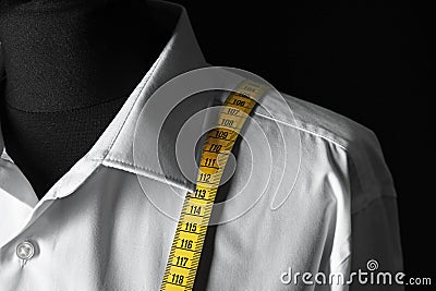 Mannequin with custom tailored shirt and measuring tape on dark background, closeup Stock Photo