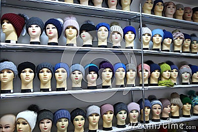 Mannequin heads in knitted hats and scarves. Mannequins female heads in hats and scarfs close up. Woolen knitted caps Stock Photo