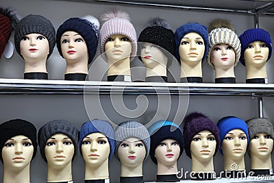 Mannequin heads in knitted hats and scarves. Mannequins female heads in hats and scarfs close up. Woolen knitted caps Stock Photo