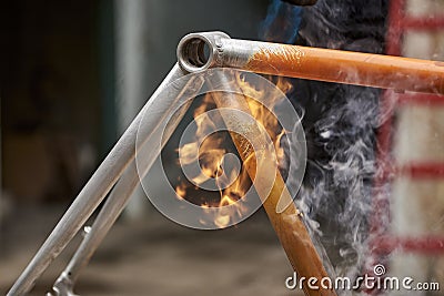 Manual bicycle renovation work, paint removal process using a torch fire Stock Photo