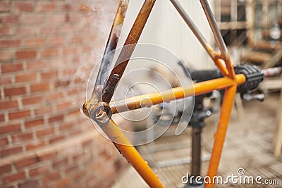 Manual bicycle renovation work, paint removal process using a torch fire Stock Photo