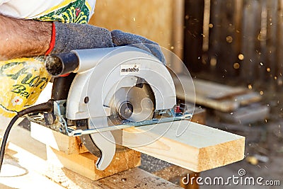Manual circular circular saw on wood metabo. A man at a construction site saws a wooden Board bar close-up. The concept of working Editorial Stock Photo