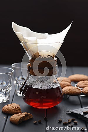 Manual coffee brewing. Hot aromatic coffee dripping through paper filter on dark wooden table Stock Photo