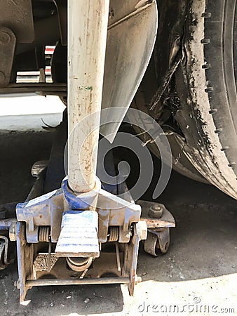 Manual mechanical jack lift jacking up a car to change burst tire in a garage Stock Photo