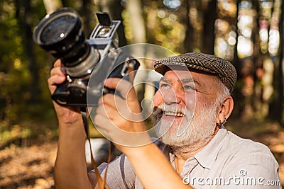 Manual settings. Pension hobby. Experienced and qualified photographer. Old man shoot in nature. Cameraman outdoors Stock Photo