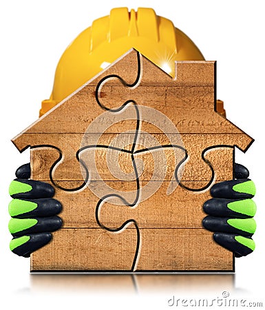 Manual Worker Holding a small Wooden House made of Puzzle Pieces Stock Photo