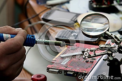 Manual worker human hand holding soldering iron tool repairing computer electronics circuit board Stock Photo