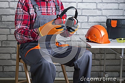 . Manual worker putting protective headphones. Stock Photo