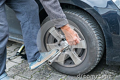 Manually tire change with four-way socket wrench Stock Photo