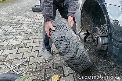 Manually tire change with four-way socket wrench Stock Photo