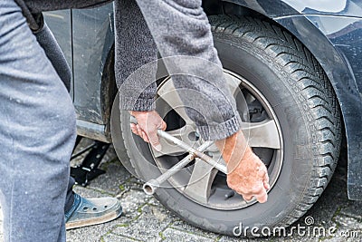 Manually tire change with four-way socket wrench Stock Photo