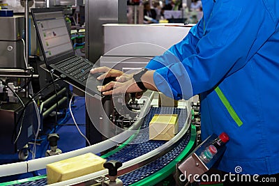 Manufacturing engineer used computer to control product inspection system automation machine in modern factory while products are Stock Photo