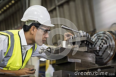Manufacturing worker. Asian mechanical engineer operating industrial lathe machine Stock Photo