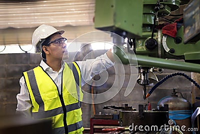 Manufacturing worker. Asian mechanical engineer operating industrial lathe machine Stock Photo