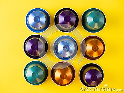 Many aluminum coffee capsules are displayed in a row on a yellow background. Food pattern. Capsules for the coffee machine. Top Stock Photo