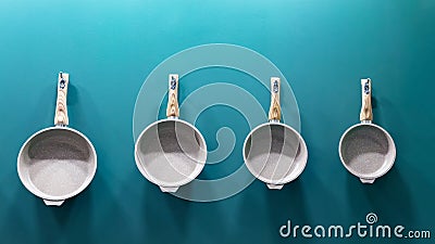 Many aluminum metal new modern cooking pans hang on the wall in the kitchen. Household goods, dishes, kitchen utensils. Storefront Stock Photo