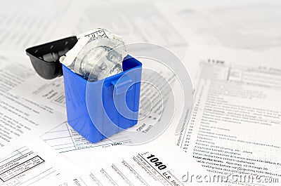 Many american tax blank forms and crumpled hundred dollar bill in trash bin Editorial Stock Photo