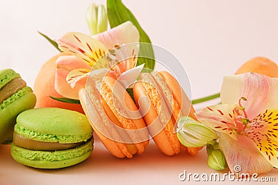 Many beige and green French macaroon cookies, yellow flower on a light Stock Photo