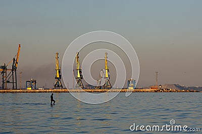 Many big cranes silhouette in the port at golden light of sunset. Mariupol, Ukraine Editorial Stock Photo
