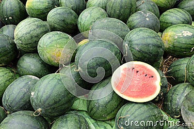 Many big sweet green watermelons and one cut half watermelon Stock Photo