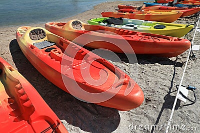 Many bright kayaks on sand near river Stock Photo