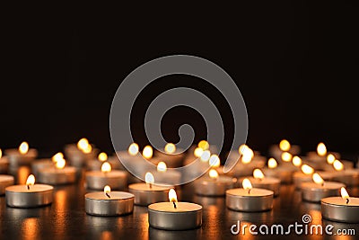 Many burning candles on table against dark background. Stock Photo