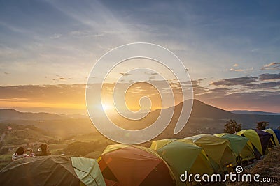 Many camping tent on green field near forest during dramatic sunrise at summer misty morning,Concept of outdoor camping adventure Stock Photo