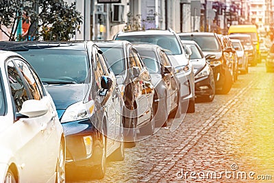 Many Cars parked in row on street in city in sunny summer day. ecological problem - air pollution Stock Photo