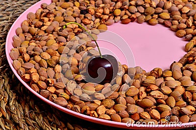 Many cherry stones on a pink plate and one cherry Stock Photo
