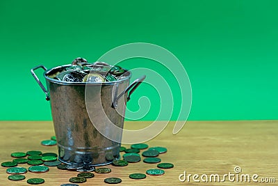 Many coins are in silver buckets on a green background. Money overflow from bucket. Coins overflow from silver bucket Stock Photo