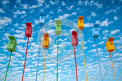 Many colored birds houses on long stems in the sky background Stock Photo