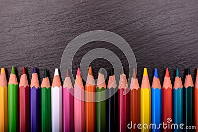 Many colored pencils on a black stone slate, place for text Stock Photo