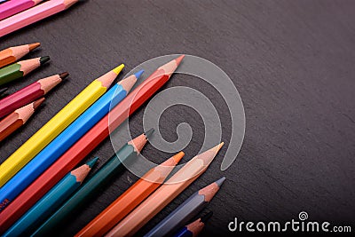 Many colored pencils on a black stone slate, place for text Stock Photo