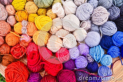 Many colorful balls, clews, wads, ravels of wool, laying in a large wooden bowl standing on the ground of green grass Stock Photo